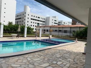 a swimming pool in front of a building at Apartamento amplo com acesso direto à praia! in Cabedelo