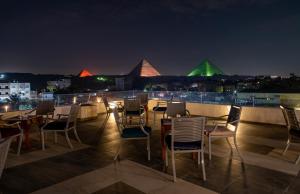 Nine Pyramids View Hotel في القاهرة: مجموعة من الكراسي والطاولات على السطح في الليل