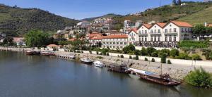 a group of boats docked on a river in a town at Alojamento Dos Santos - Pinhão in Pinhão