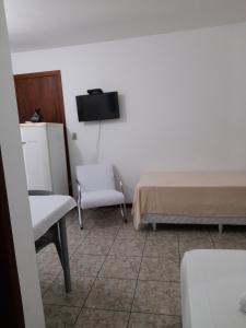Habitación con 2 camas, silla y TV. en Pousada Baleia Franca Canasvieiras en Florianópolis