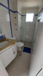 a white bathroom with a toilet and a sink at Apto Frente ao Mar in Bertioga