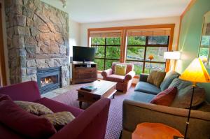 a living room with couches and a stone fireplace at Lodging Ovations in Whistler
