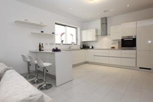 a white kitchen with a counter and stools in it at Villas Flamingo Resort in Adeje