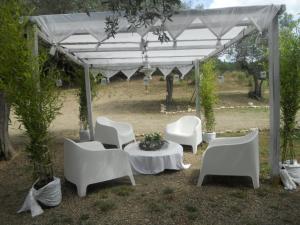 een groep witte stoelen en een tafel onder een luifel bij Splendid Holiday Home in Rignano Sull Arno FI with Garden in San Cristoforo a Perticaia