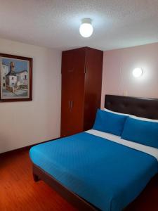 a bedroom with a blue bed and a cabinet at Hotel Valle de Pubenza in Popayan