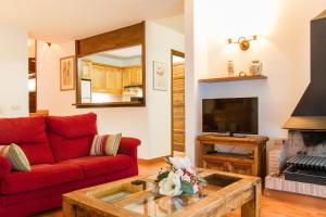 a living room with a red couch and a fireplace at Refugi d' Inclès B4 in Canillo