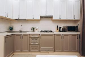 a kitchen with white cabinets and a microwave at Apart-smart on Kharkovskaya near Lavina 1 floor in Sumy