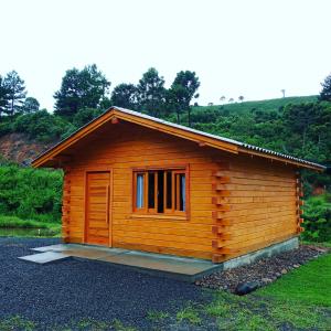 a small wooden cabin with a window in a field at Cabana da Colina in Bom Jardim da Serra