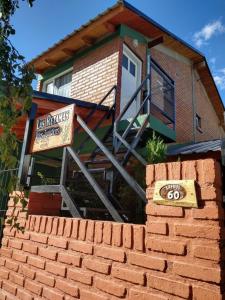 une maison avec un panneau au-dessus d'un mur de briques dans l'établissement Las Retamas - Viviendas Turísticas, à Zapala