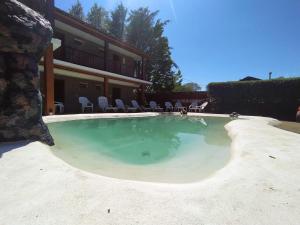 a large swimming pool with chairs and a house at Hotel Berlin in Villa General Belgrano