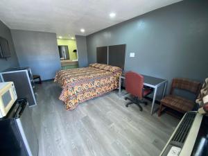 a hotel room with a bed and a desk and a chair at Town House Motel in Tyler