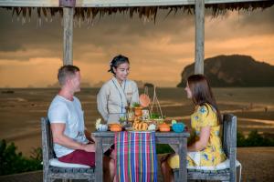 a group of people sitting at a table on the beach at Koh Yao Yai Village - SHA Extra Plus in Ko Yao Yai