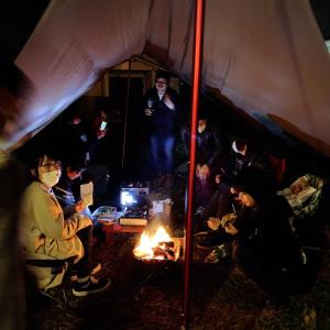 a group of people sitting around a fire in a tent at yado & kissa UGO HUB in Yuzawa