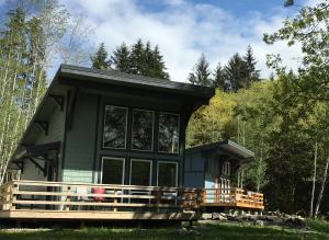 a green house with a large deck in the woods at Hoh Valley Cabins in Forks
