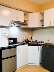 uma cozinha com armários brancos e um aparelho preto em Zen Living Condo at Avida Atria Tower 2 em Iloilo
