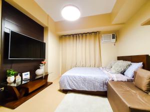 a bedroom with a bed and a flat screen tv at Zen Living Condo at Avida Atria Tower 2 in Iloilo City