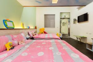 a pink bedroom with two beds and a tv at 曉翠軒親子民宿 in Wujie
