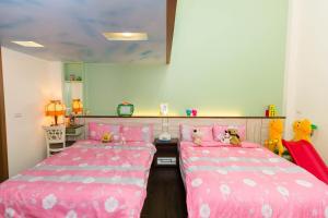 two beds in a room with pink sheets and stuffed animals at 曉翠軒親子民宿 in Wujie