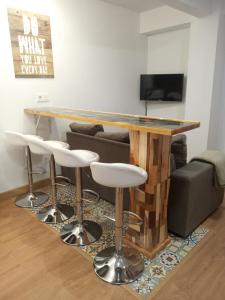 un bar en una sala de estar con mesa y taburetes en Alojamiento en Gijon perfecto para conocer Asturias, en Gijón