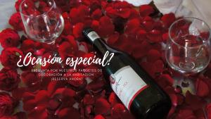 una botella de vino y dos copas en una mesa con rosas rojas en Posada y Spa Jade Teotihuacan, en San Juan Teotihuacán
