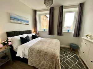ein Schlafzimmer mit einem Bett und zwei Fenstern in der Unterkunft Central Apartment Linlithgow in Linlithgow