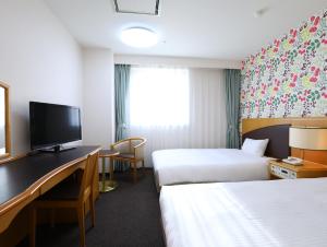 Habitación de hotel con 2 camas y escritorio con TV. en Hotel Wing International Tomakomai, en Tomakomai