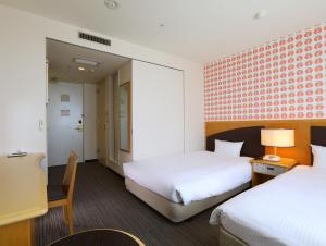 a hotel room with two beds and a chair at Hotel Wing International Tomakomai in Tomakomai