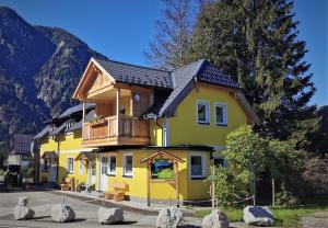 Una casa amarilla con balcón en la parte superior. en Ferienwohnungen ARIKOGEL Bad Goisern, en Bad Goisern