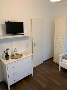 a bedroom with a white dresser with a tv on top at Zum armen Mann in Düsseldorf