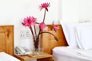 wazon z różowymi kwiatami na stole obok łóżka w obiekcie Khách sạn Thái Bình w mieście Con Dao