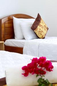 Duas camas com lençóis brancos e um ramo de flores cor-de-rosa em Khách sạn Thái Bình em Con Dao