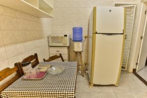 a kitchen with a table and a refrigerator at Suítes Pitangueiras Guarujá in Guarujá