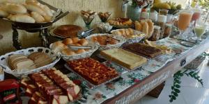 a table filled with different types of bread and pastries at Pousada Vale do Amanhecer in Cabo Frio