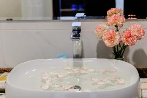 a white sink with pink flowers and a vase of flowers at Malina Luxury Villa in Da Thien