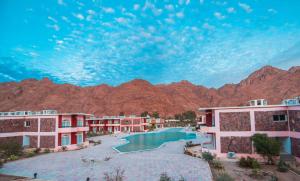 a resort with a pool and mountains in the background at Morgenland Holly Village in Saint Catherine