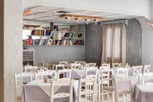 una sala da pranzo con tavoli bianchi e sedie bianche di Amaryllis Hotel a Perissa