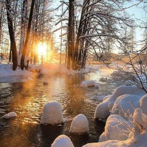 a river covered in snow with the sun in the background at University Hotel Tsakhkadzor in Tsaghkadzor
