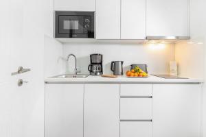 a white kitchen with a sink and a microwave at Feel like an Emperor Apartments in Split