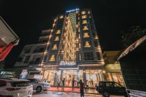 贡布Twin Hotel Kampot的一座高大的建筑,前面有人站在