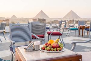 Nine Pyramids View Hotel في القاهرة: صحن فاكهة على طاولة مع الاهرامات في الخلفية