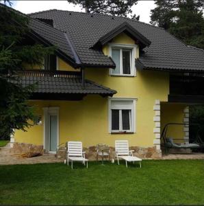 PalisatにあるYellow Houseの庭に3脚の椅子とテーブルがある黄色い家