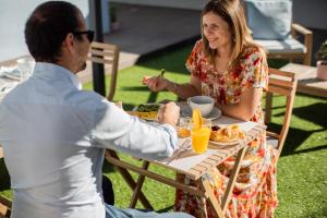 un hombre y una mujer sentados en una mesa comiendo comida en MyStay Matosinhos Centro, en Matosinhos