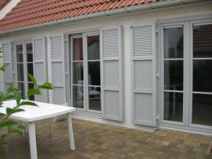 a house with white windows and a white bench at Floris'Home in De Haan