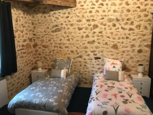 Habitación con 2 camas individuales y pared de piedra. en La Grenouille, en Saint-Adjutory