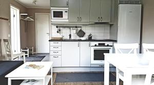 a kitchen with white cabinets and a white table at Nybyggd stuga intill skogsbrynet - New built cottage next to the cowberry forest in Mora