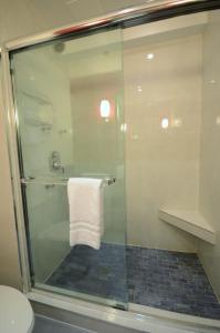 a bathroom with a glass shower with a towel at Armon Plaza Montreal Airpt, Trademark Collection by Wyndham in Montreal