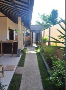 a walkway in front of a building with grass at Meisya Cottage in Gili Trawangan