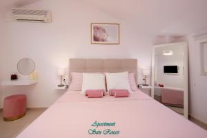 a bedroom with a large white bed with two pink pillows at Apartment San Rocco in Stinica