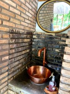 a copper sink in a brick wall with a mirror at Pousada Vilarejo in Itacaré