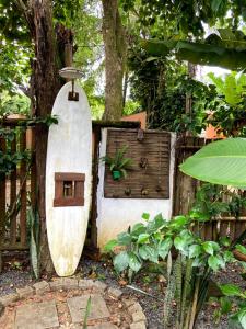 una tabla de surf apoyada en una valla con una casa de aves en Pousada Vilarejo en Itacaré